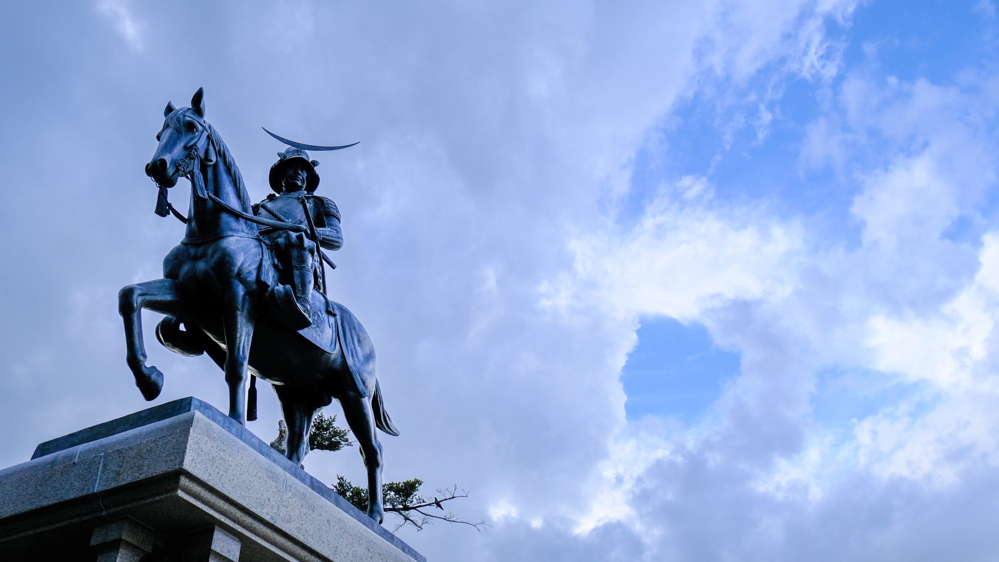 A statue of a samurai, with blue sky in the background