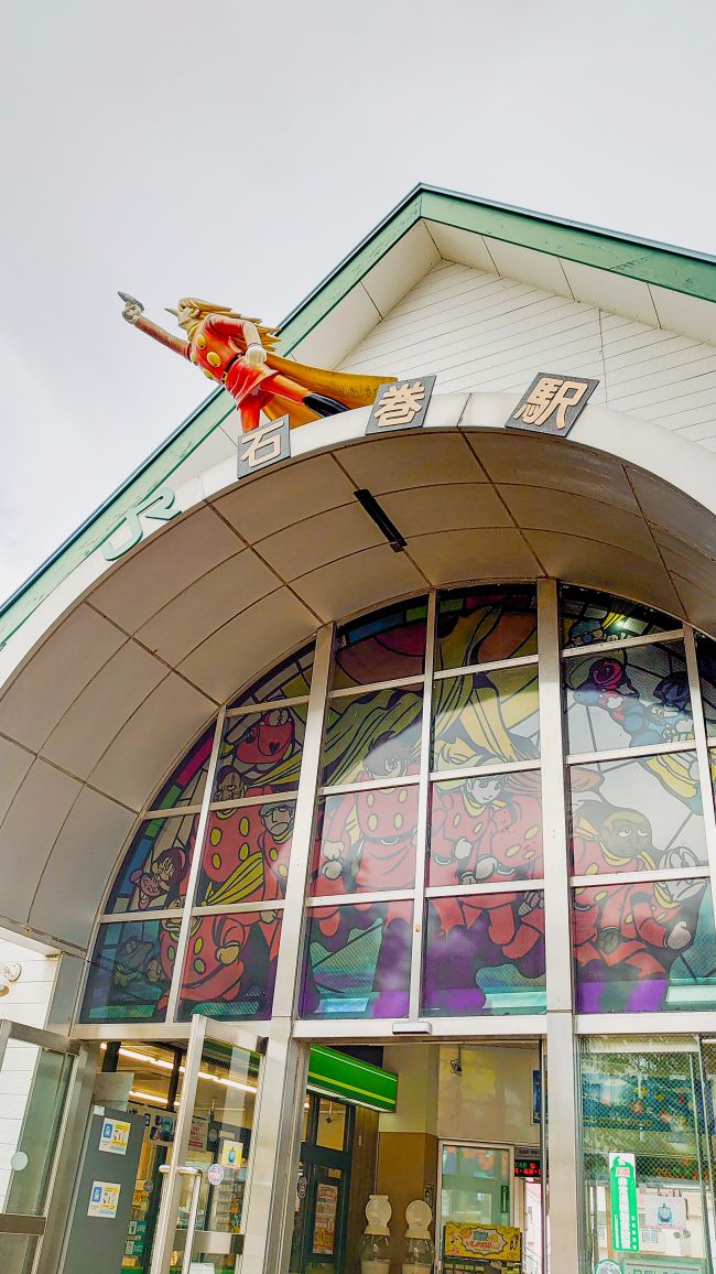 Entrance of a station with a statue of a comic character on the roof