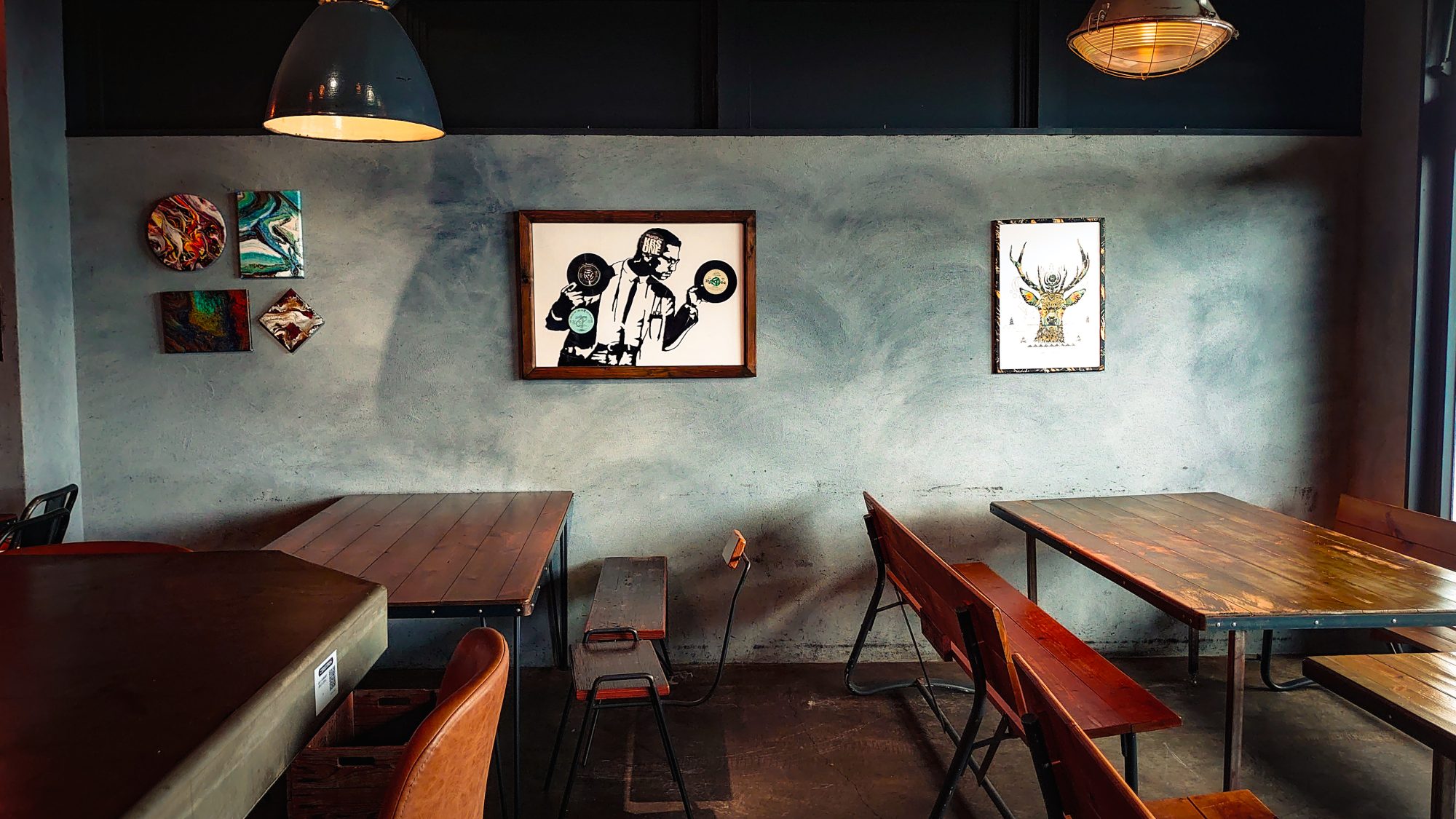 A photo of cafe with tables and chairs, artworks on the wall